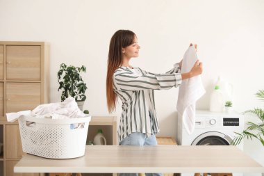 Çamaşır odasında temiz havlusu olan genç bir kadın.