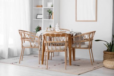 Masası, hasır sandalyeleri ve beyaz duvarın yanındaki raf ünitesi olan yemek odasının içinde.