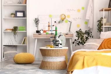 Modern mikroskop ve kimyasal şişeler şık bir gencin odasındaki hasır masada.