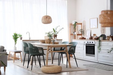 Masa, sandalye ve hasır pouf yemek odasının içinde tezgahın yanında.