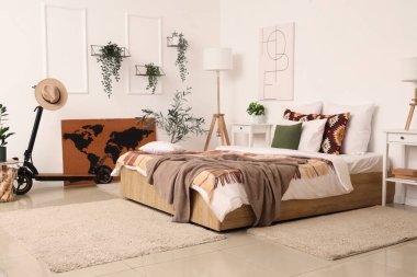 Elektrikli scooter, bitkiler ve lambayla aydınlık yatak odasının içinde.