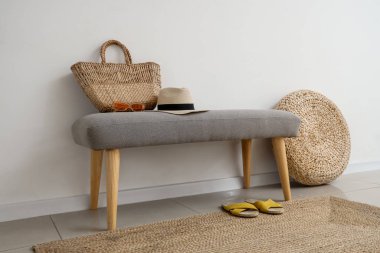 Salondaki ışık duvarının yanında yaz aksesuarları olan yumuşak bir bank.