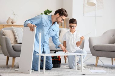 Baba ve küçük oğlu evde raf montajı yapıyor.