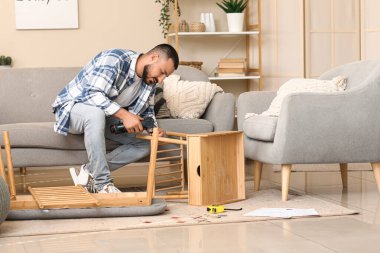 Evinde ahşap masa montajı yapan genç bir adam.