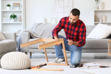 Young man assembling table at home