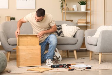 Evdeki çekmecede ahşap masa montajı yapan genç adam.