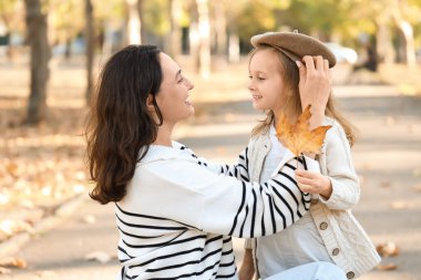 Güzel sonbahar parkında küçük tatlı kızıyla mutlu bir anne.