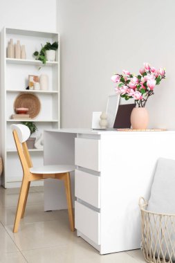 Işık odasındaki masasında manolya çiçekli vazo.