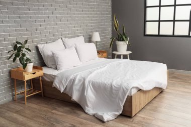 Modern yatak odasının iç kısmında battaniyeli beyaz yastıklar.