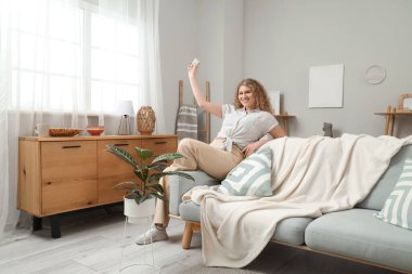 Oturma odasında klimalı, gülümseyen genç bir kadın.