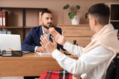 Erkek avukat, ofiste tekerlekli sandalyedeki adamı dinliyor.