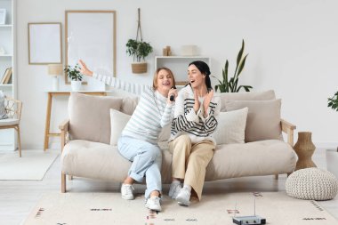 Evde mikrofonlu güzel genç kadınlar karaoke yapıyor.