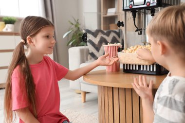 Evde patlamış mısır makinesi olan küçük çocuklar.