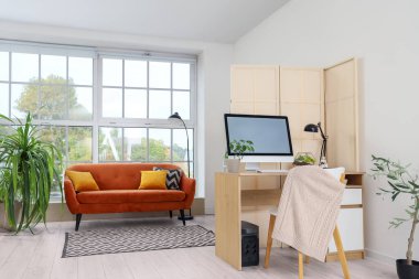 Kahverengi kanepesi, katlanır perdesi ve rahat çalışma yeri olan şık bir oturma odası.