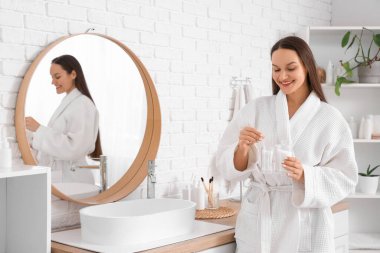 Banyoda pamuk tomurcuğu tutan genç bir kadın.