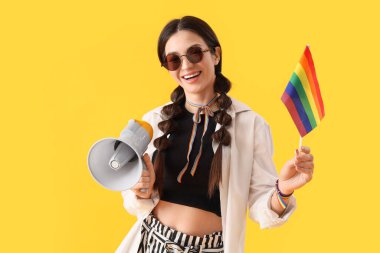 Gökkuşağı bayrağı ve sarı arka planda hoparlörü olan güzel bir genç kadın. LGBT kavramı