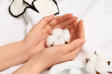 Beyaz havluda pamuk çiçekli kadın eller, yakın plan.