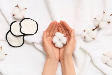 Beyaz havluda pamuk çiçekleri olan kadın eller, yakın plan.