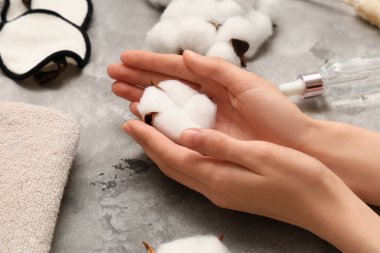 Gri grunge arka planda pamuk çiçekli kadın elleri, yakın plan