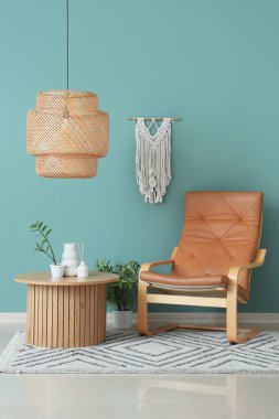 Oturma odasının içindeki yeşil duvarın yanında rahat bir koltuk, masa ve bitkiler.