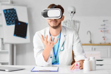 Klinikteki masada VR gözlüğü kullanan bir erkek doktor.