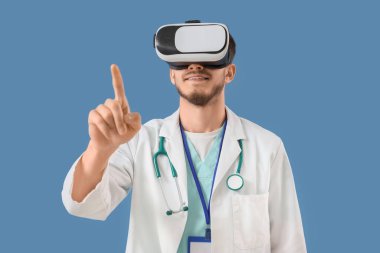 Mavi arka planda sanal ekran kullanan VR gözlüklü erkek doktor