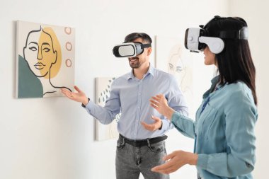 Sanat galerisinde gözlüklü genç bir çift resimlere bakıyor.