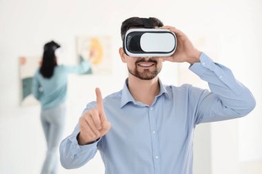 Sanat galerisinde VR gözlük kullanan genç adam.
