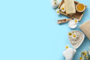 Papatya çiçekleri, kozmetik ürünlü kaseler ve mavi arka planda deniz tuzu.