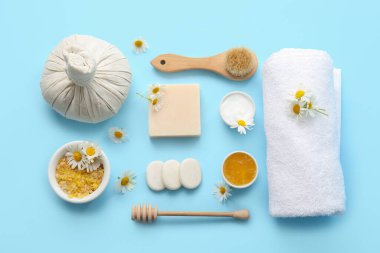 Havlu, spa taşları ve mavi arka planda papatya çiçekli kompozisyon, yakın plan.