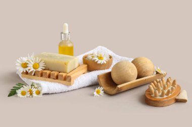 Masaj vücut fırçası, kozmetik ürün şişesi ve gri arka planda papatya çiçeği kompozisyonu, yakın plan.