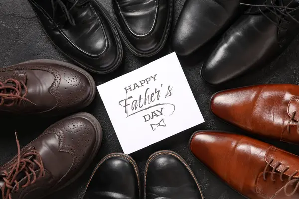 Farklı bir adamın ayakkabıları ve siyah arkaplanda Mutlu Babalar Günleri yazılı tebrik kartı.