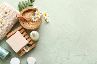 Sabun barlı kompozisyon, papatya çiçekleri ve yeşil grunge arka planda deniz tuzu olan kase, yakın plan.