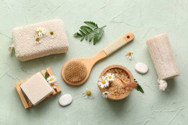 Sabun kalıbı, masaj vücut fırçası, papatya çiçeği ve yeşil grunge arka planında deniz tuzu olan kase, yakın plan.