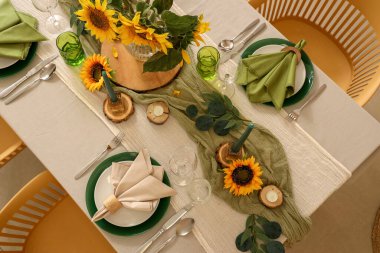 Tabaklar, mumlar ve güzel ayçiçekleri olan zarif bir masa.