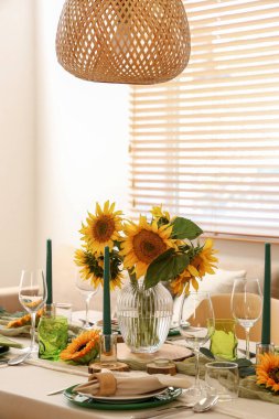 Tabaklar, mumlar ve güzel ayçiçekleri olan zarif bir masa.