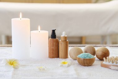 Kuaför salonundaki masaj masasında spa aksesuarları, kozmetik ürünleri ve tropikal çiçeklerle kompozisyon