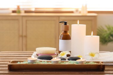 Spa aksesuarları, kozmetik ürünleri ve kuaför salonundaki ahşap masada yanan mumlar.