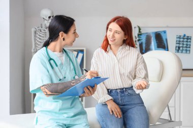 Klinikte genç bir kadınla çalışan dövmeli bir kadın doktor.