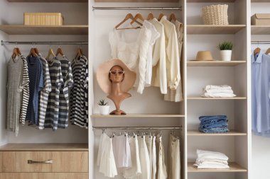 Raflı gardırop, manken kafası ve soyunma odasında giysiler.