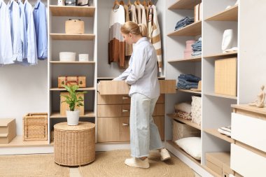 Genç bir kadın gardıroptaki çekmeceyi açıyor.