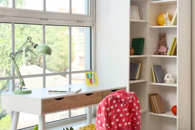 Kitap rafı ve çalışma masası olan çocuk odasının içi