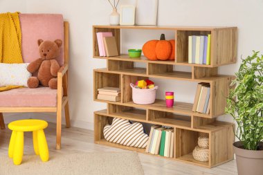 Kitaplığı, koltuğu ve oyuncakları olan hafif çocuk odasının içi.