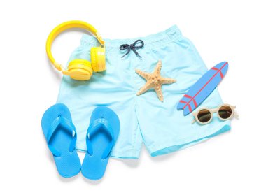 Beyaz arka planda plaj aksesuarları olan çocuk yüzme şortu.