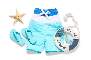 Beyaz arka planda plaj aksesuarları olan çocuk yüzme şortu.
