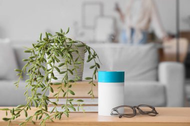 Gözlüklü hava nemlendirici, bitki ve kitaplar oturma odasında, yakın plan.