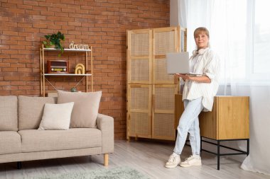 Evde laptop kullanan olgun bir kadın.