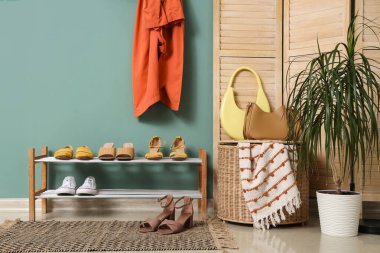 Ayakkabı standı, sepeti ve palmiye bitkisi olan şık bir koridor.