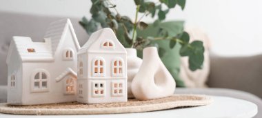 Hasır paspas, ev mumu tutacakları ve yeşil dallı vazolar oturma odasında, yakın plan.