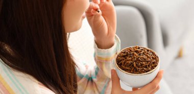 Güzel Asyalı kadın evde kızarmış böcek yiyor, yakın plan.